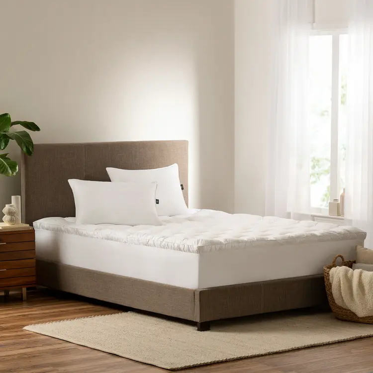 Serta Down Illusion Pillowtop Mattress Topper on top of a mattress with two pillows on top