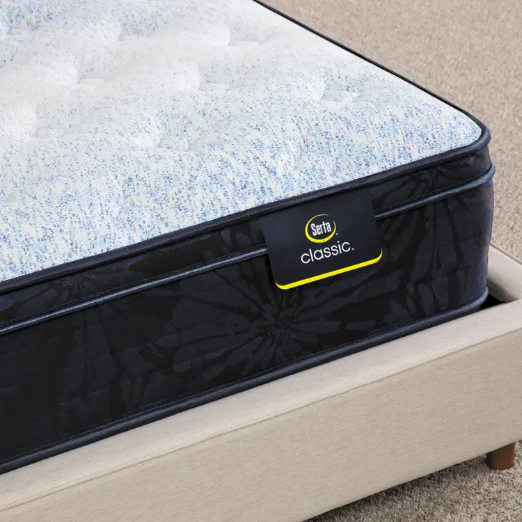 Corner of Serta classic dorian plush euro top mattress sitting in a beige bed frame ||feel: plush euro top ||level: standard