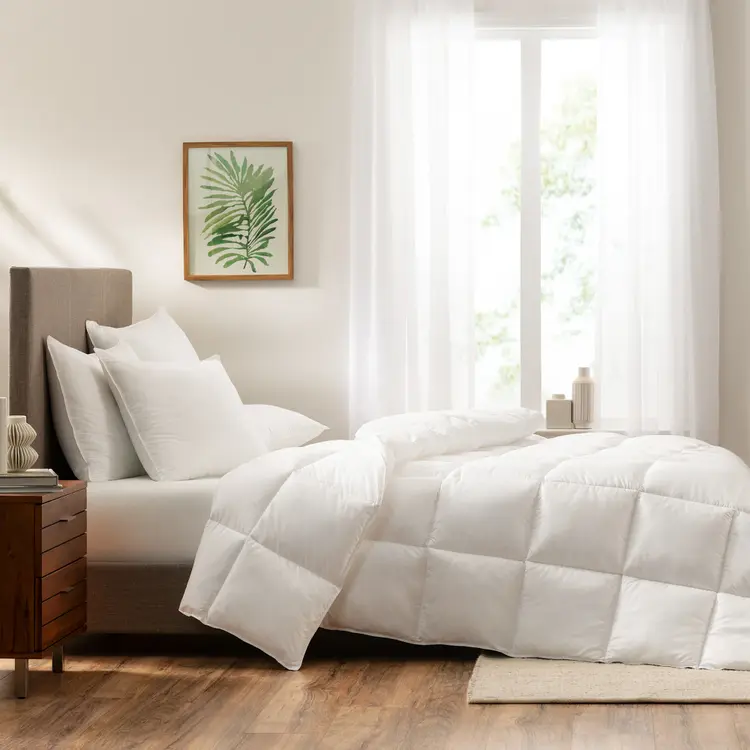 The Serta Light Down Illusion Down Alternative Comforter on a mattress in a bedroom